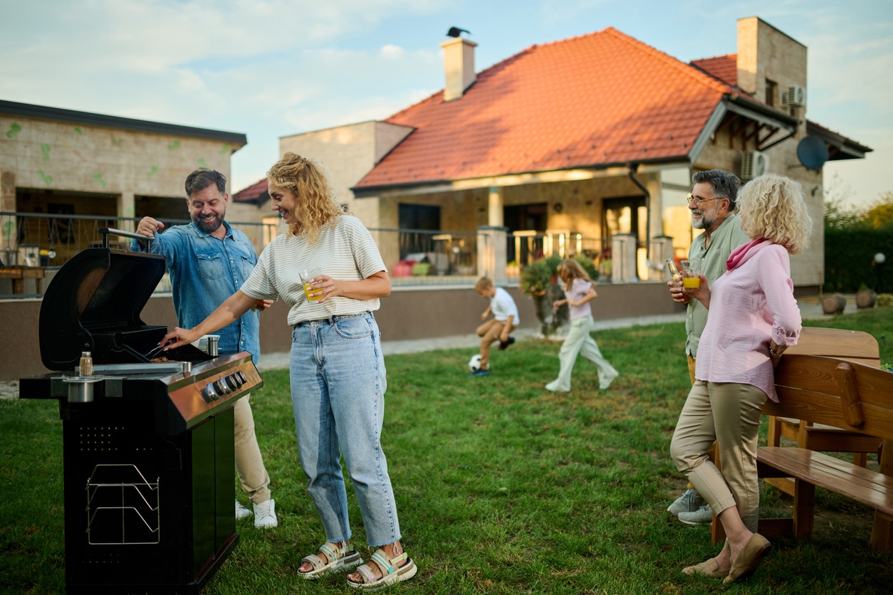 A family gathers in the backyard for a BBQ party after some summer lawn care prep.