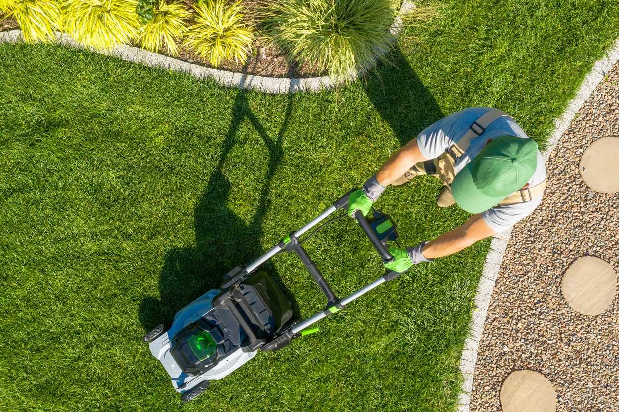 A Birmingham homeowner mows his lush green grass in his neatly landscaped backyard.