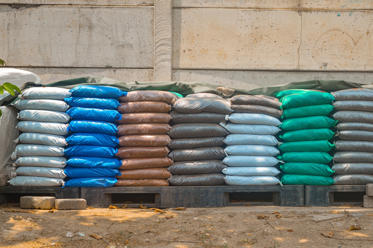 Stacked fertilizer bags on a pallet, showcasing various types for sod